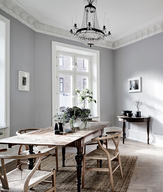 a vintage Scandinavian dining room with a vintage shabby table and woven chairs, a crystal chandelier and a jute rug