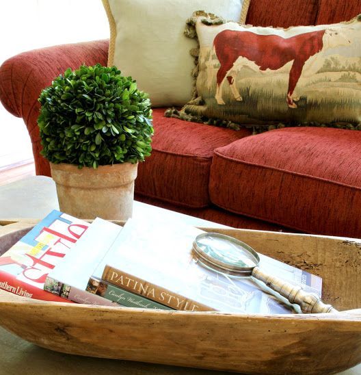 an antique dough bowl used for storing books, magazines and other coffee table stuff