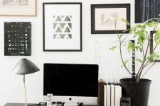 an elegant Scandinavian home office with a black trestle desk, a leather chair and a black and white gallery wall