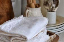 kitchen towels stored in a vintage dough bowl is a cool idea for a rustic kitchen