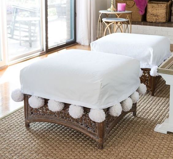 rattan ottomans with white covers and large white pompoms are amazing to give a chic feel to the space