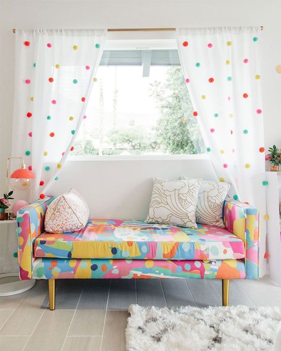 simple white curtains accented with colorful pompoms to match the loveseat