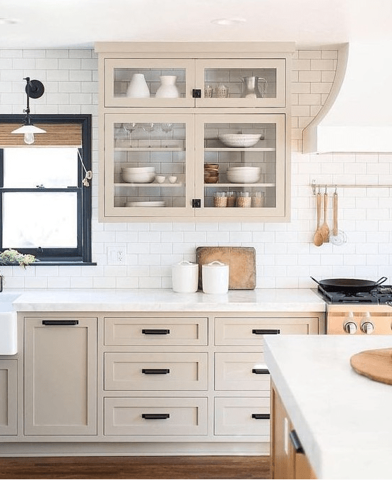 a beautiful light stained shaker style kitchen with a white subway tile backsplash and white quartz countertops plus black fixtures