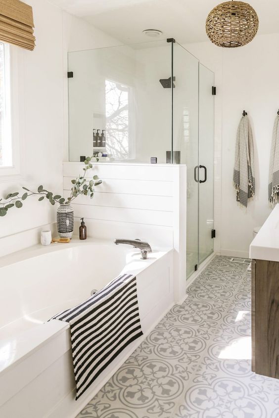 a boho neutral bathroom with beadboard, printed tiles, a wooden vanity, printed textiles, a woven lamp and a shower space