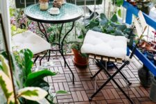 a bright balcony with a coffee table and folding chairs, potted greenery and blooms is a cool and bold space