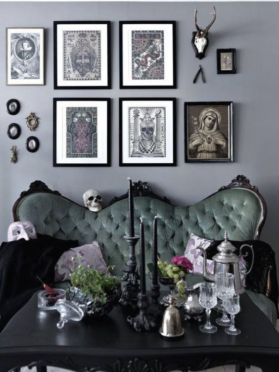 a chic Gothic living room with grey walls, a refined green sofa, a black table and a catchy gallery wall and candles