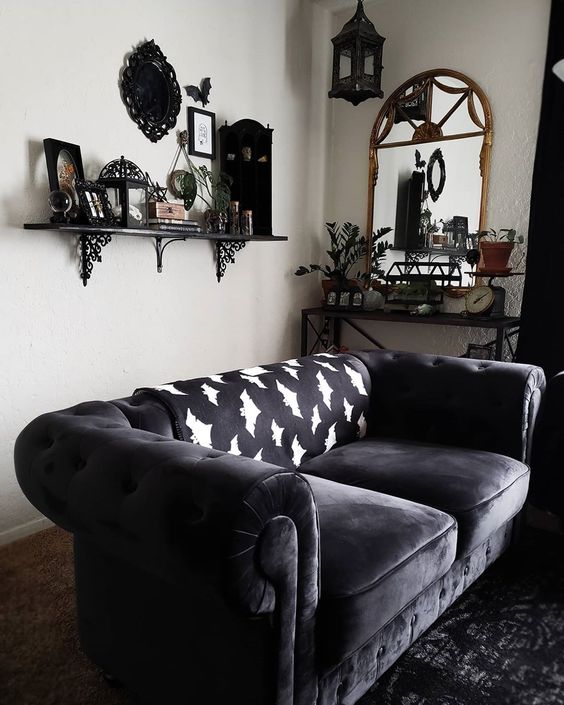 a chic Gothic living room with white walls, dark furniture, a shelf with cool objects on display and potted greenery