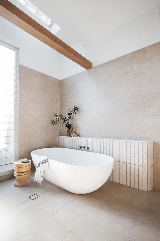 a contemporary bathroom with a neutral panel and a wooden beam, an oval tub and a wooden side table