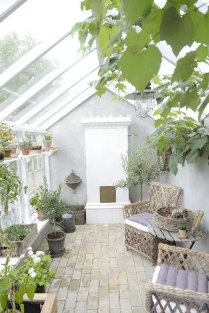 A cozy Scandi sunroom with a non working fireplace, woven chairs, a wooden table with a basket, potted plants