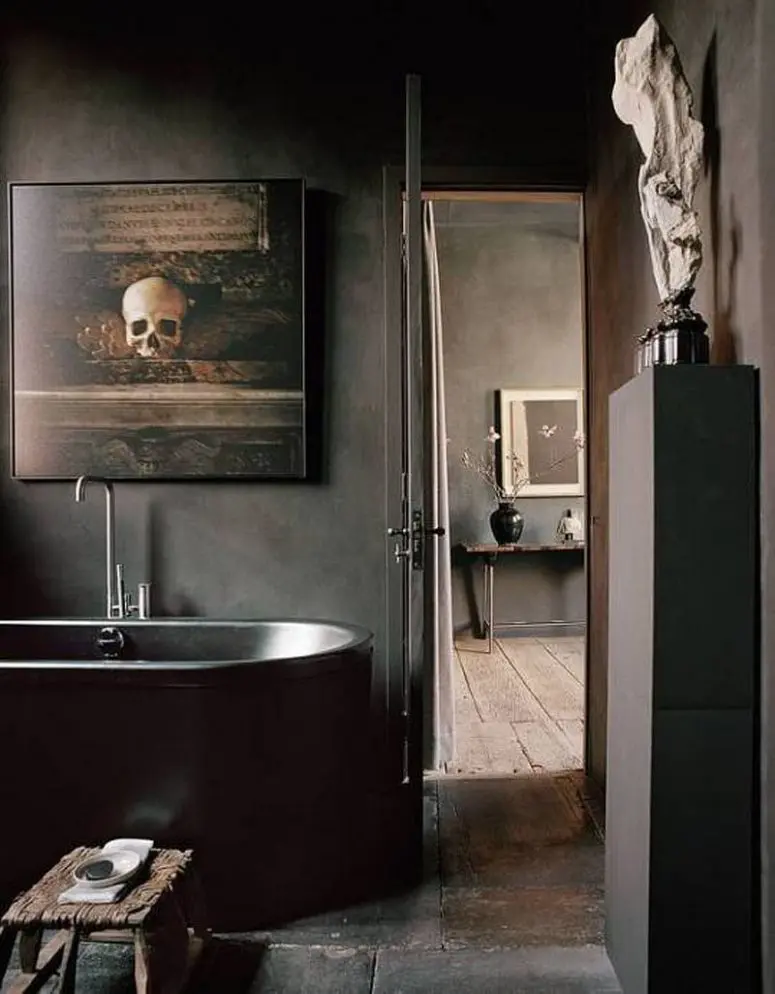 a delicate Gothic bathroom in black, with concrete walls, a stone tub, a rough wooden stool and a beautiful vintage artwork