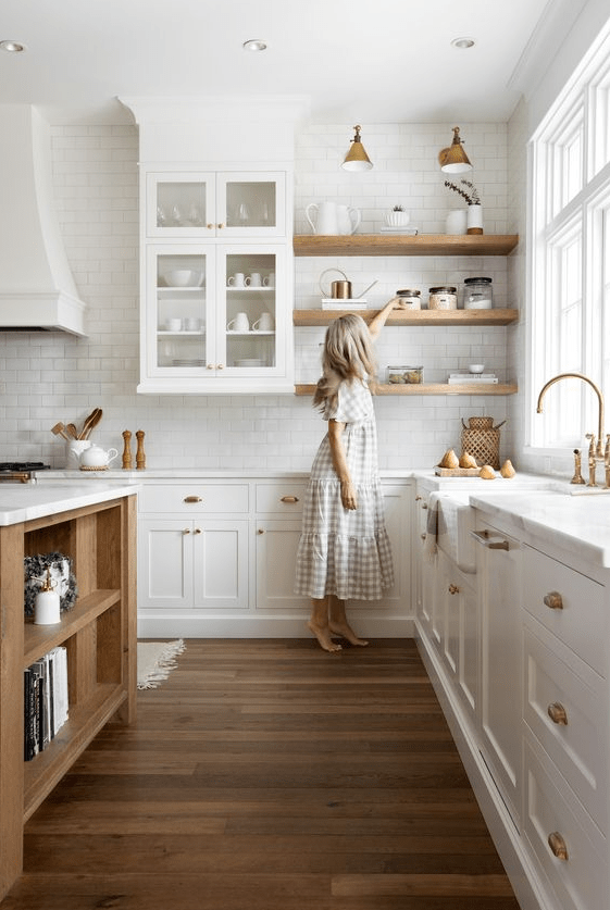 a delicate creamy kitchen with inlay and glass cabinets, open shelves, white quartz counterops, stained shelves and a stained kitchen island