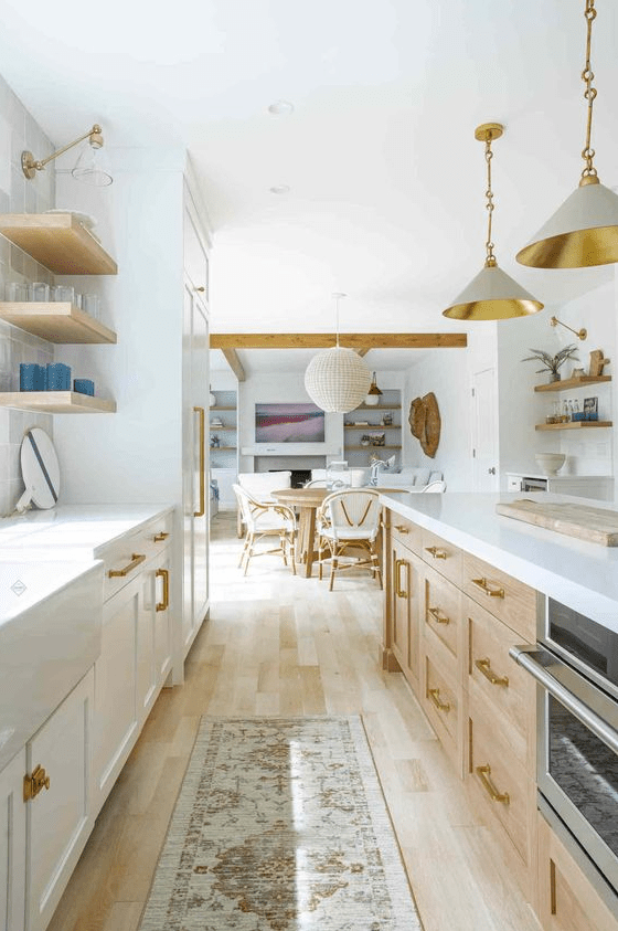 A light filled farmhouse galley kitchen with white and stained cabinets, open shelves, pendant lamps and white stone countertops