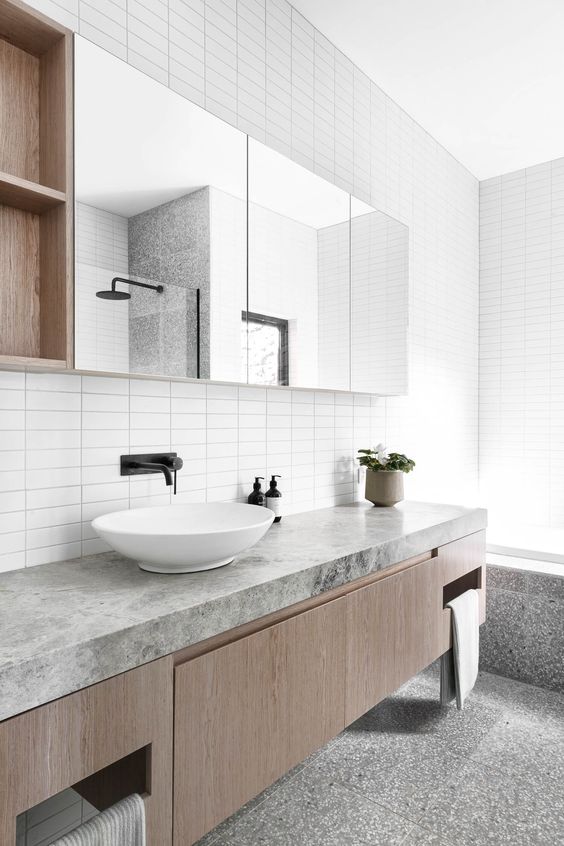 a minimalist grey and white bathroom with a floating vanity with a stone countertop, a mirror with storage compartments and a bathtub
