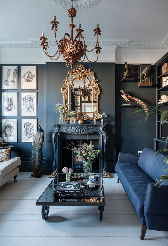 a modern Gothic living room with black walls, ablue and white sofa, a fireplace, a refined chandelier and mirror, catchy artworks