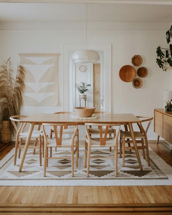 a modern boho dining space in neutrals, with a wooden dining set, printed textiles, decorative baskets and pampas grass