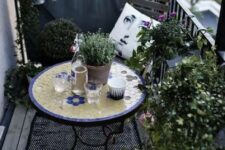 a monochromatic balcony with chairs and a lot of potted greenery is spruced up with a colorful mosaiic table