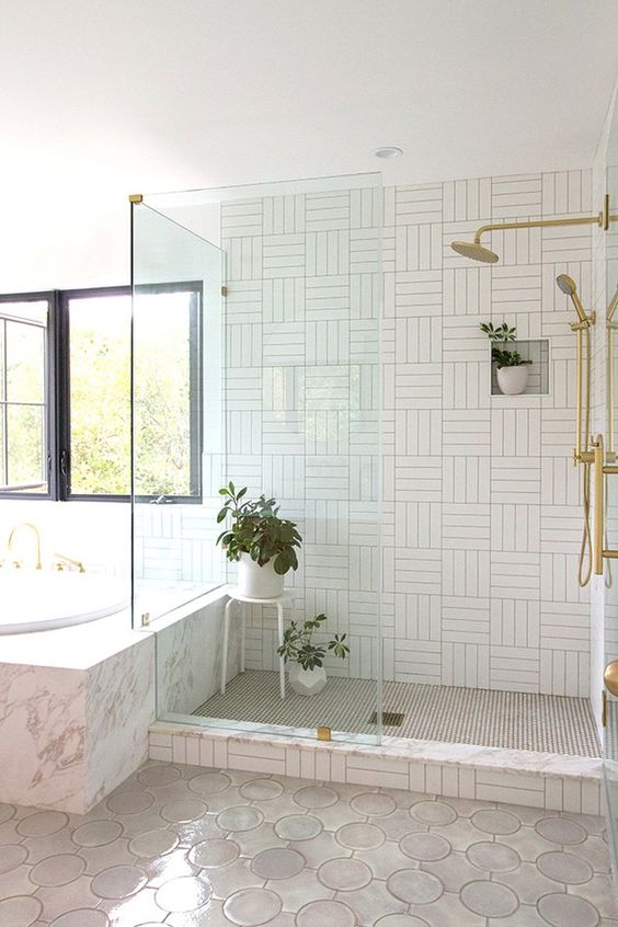 a neutral bathroom with mismatching tiles, potted greenery and gold fixtures is a stylish idea with a modern feel