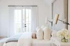 a neutral bedroom with an upholstered bed, neutral bedding, a printed rug and a chic retro chandelier