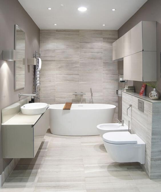 a neutral contemporary bathroom clad with grey tiles, with white appliances and a floating vanity plus built-in lights