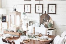 a neutral vintage farmhouse dining room with planked walls, a dark stained table, white chairs and upholstered loveseats