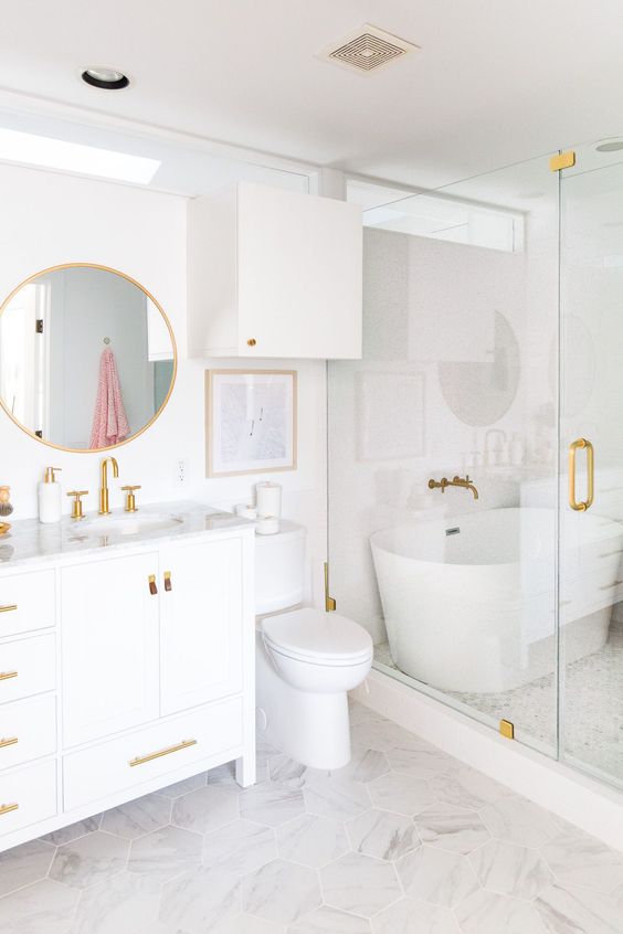 a refined bathroom with a vanity, white appliances and a shower space, gold fixtures and other touches for a more chic look