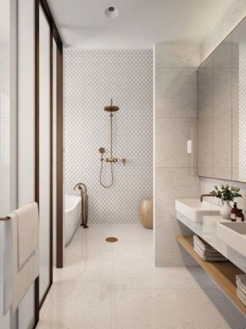 a refined contemporary bathroom with penny, large scale tiles, a floating vanity and a bathtub plus brass touches