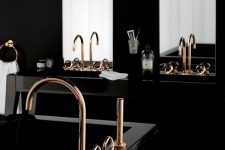 a refined modern Gothic bathroom with a black vanity and a polished tub, gold fixtures, tall mirrors and a black chandelier