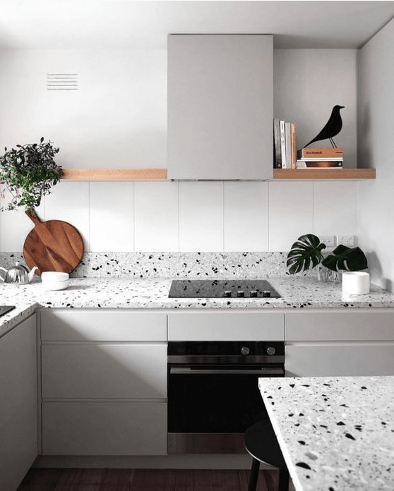 a serene Nordic kitchen with light grey cabinets and matching grey terrazzo countertops and a long open shelf instead of uppers