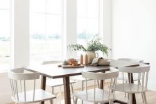a small airy dining room with a stained table and vintage white chairs, some greenery is a very welcoming and cool space
