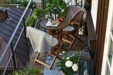 a small and cozy balcony with potted greenery, wooden folding IKEA furniture, potted blooms and candle lanterns