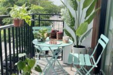 a small and stylish balcony with mint blue folding furniture, potted blooms and plants and a cool view
