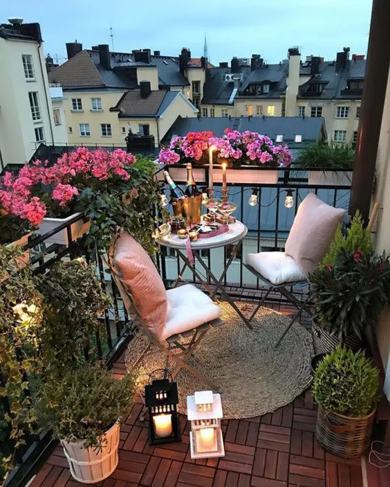 a small balcony with folding furniture, greenery and blooms plus string lights and candle lanterns is cool