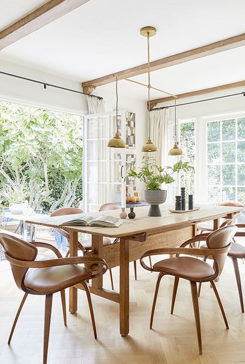 a stylish dining room with a stained wooden table, leather and wood chairs, a cool pendant lamp and beams on the ceiling