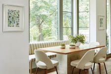 a stylish mid-century modern dining space by the window, with a large striped sofa, a table and creamy chairs and a gorgeous view
