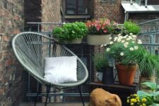 a summer balcony with potted greenery and blooms, a chair, a rug and candles