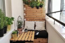 a tiny balcony with a built-in storage bench, a folding table and a chair, potted greenery and printed boho textiles