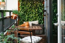 a tiny balcony with a living wall and potted plants, IKEA outdoor furniture and some printed pillows and lights