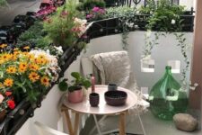 a tiny summer balcony with lots of potted blooms, wooden and metal furniture and pretty accessories