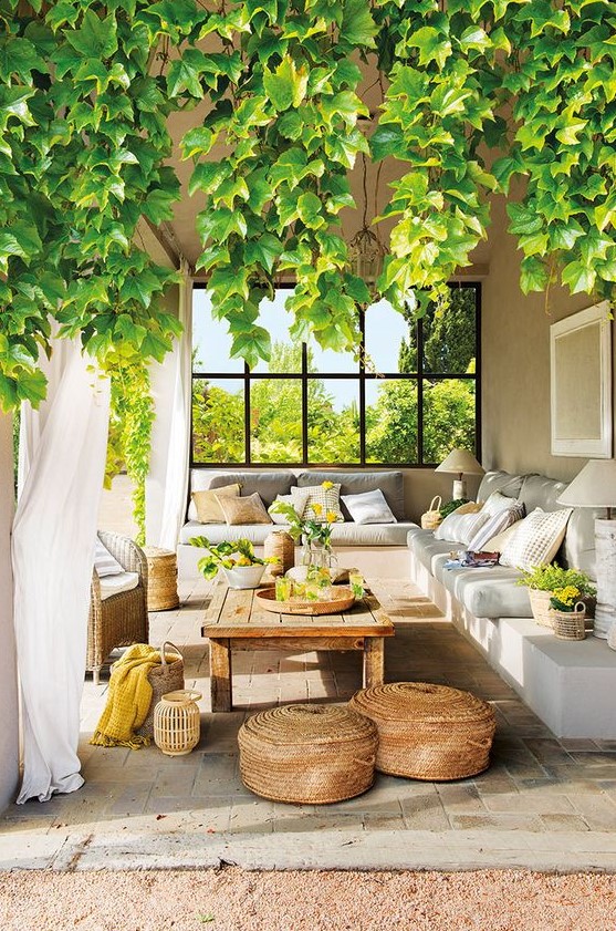 a welcoming Mediterranean terrace with a built-in corner sofa, a low wooden table, baskets, lanterns and greenery and blooms