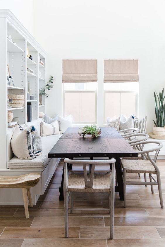 A welcoming neutral dining space with a built in bench, a dark stained table, woven chairs and cool shades is very welcoming
