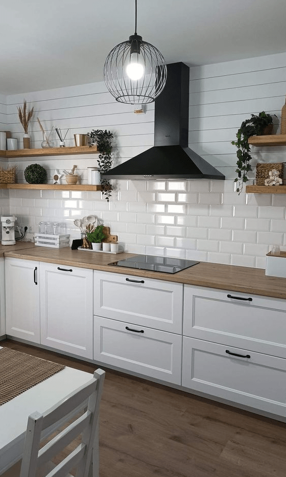 a white Nordic kitchen with shaker cabinets, a white subway tile backsplash, open shelves and a black hood