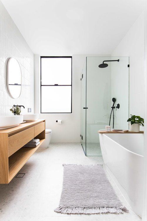 an airy contemporary bathroom with a floating vanity, an oval tub, a glass enclosed shower space and black fixtures