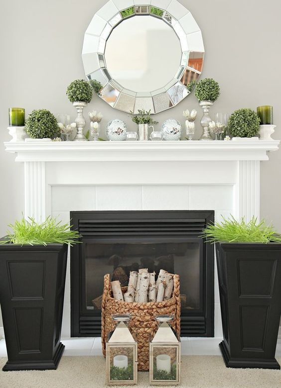 tall black planters with wheatgrass, a basket with firewood, greenery topiaries on stands and mercury glass candleholders
