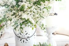a basket tray with potted greenery, a vase with white blooming branches is a lush spring decoration