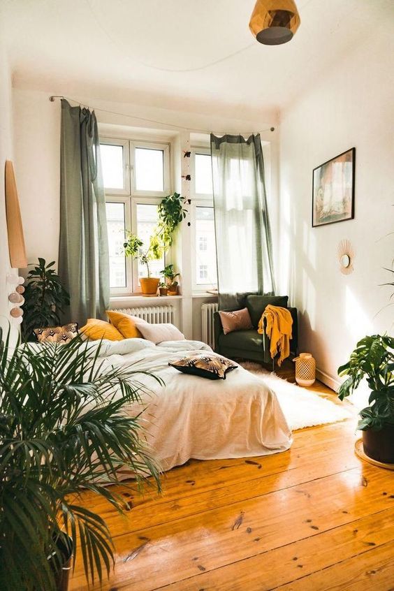 a boho bedroom with green and mustard textiles, candle lanterns, potted plants and catchy lamps