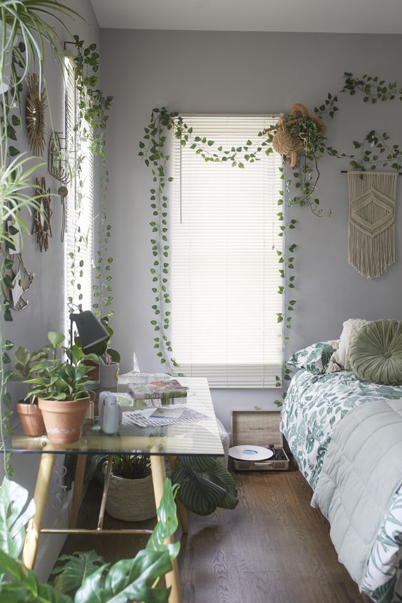 a boho spring bedroom with lots of potted greenery, macrame and botanical bedding
