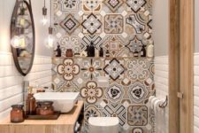 a bright and small bathroom with a mosaic tile wall, a floating wooden vanity, a tub, a round mirror and bulbs