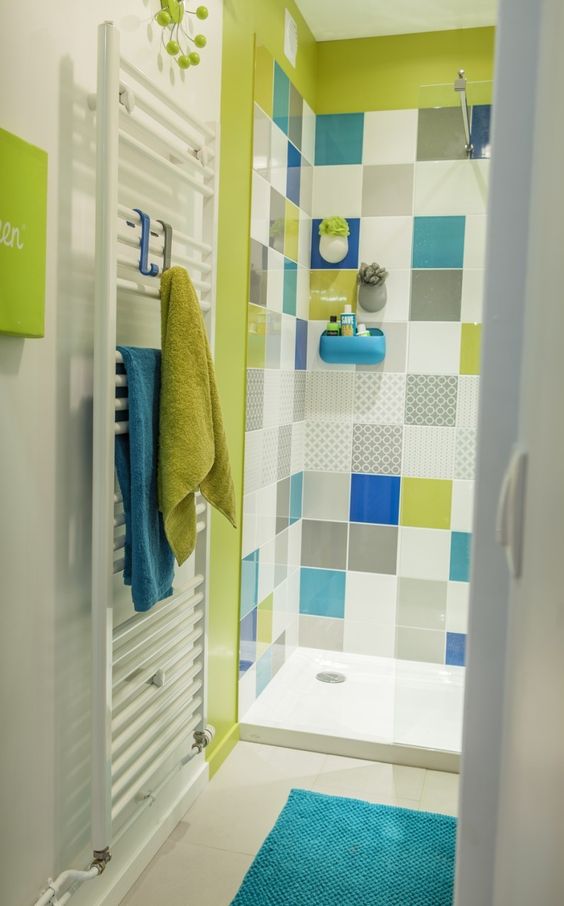 A bright bathroom in white accented with a neon green shower and multi color tiles, with neon green and blue textiles