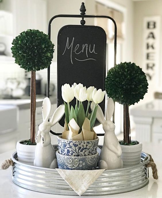 a bucket tray with greenery topiaries, white tulips and bunnies for a farmhouse spring feel in the kitchen