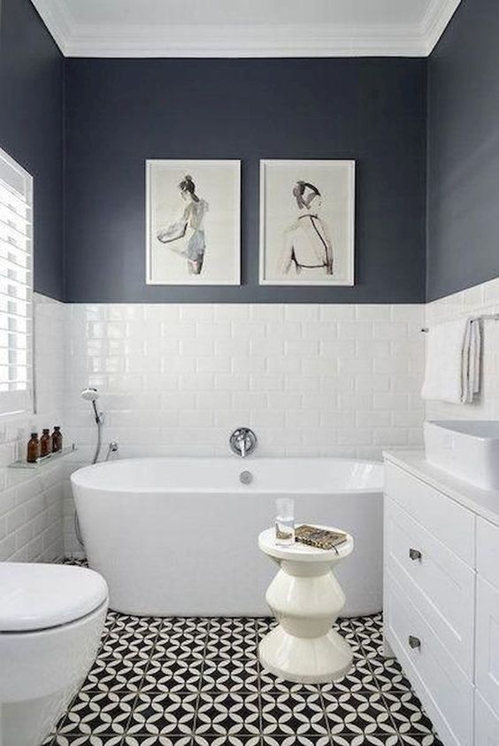 a chic black and white bathroom with a mosaic floor, black and white walls, a tub and a white vanity